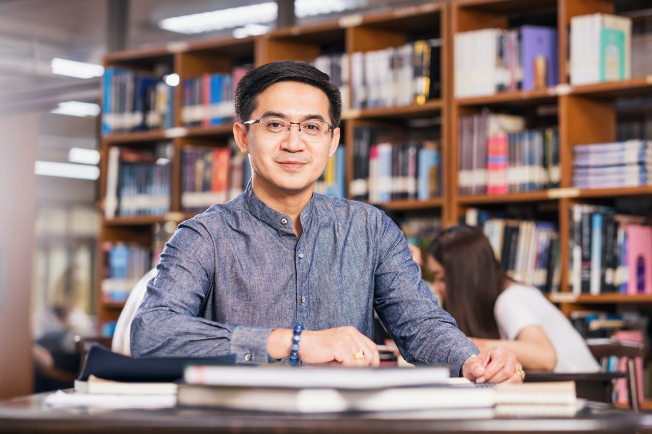 portrait asian teacher sitting in the library